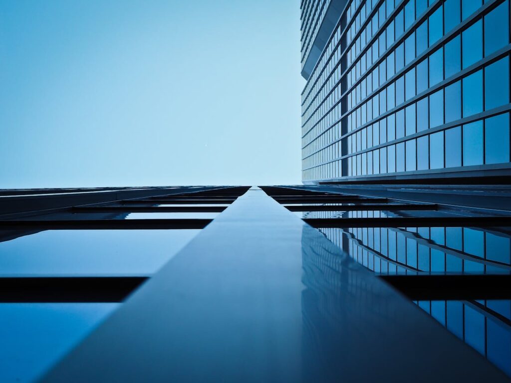 Low angle view of a modern skyscraper with reflective glass facade and blue sky.